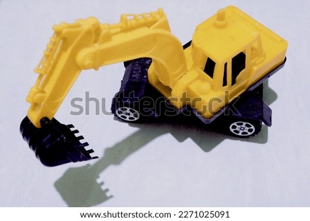 Toys photography. Yellow plastic escavator toy isolated on white background with shadow reflection selective focus.