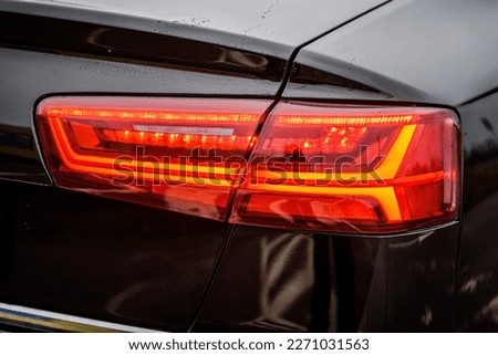Right back modern headlight car. Car taillight. Detail black metallic car with rear light close up. Rear lamp signals for turning car on street. Signal function to keep them distance. Trunk closeup.