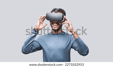 Young man using virtual reality headset. Isolated on gray background studio portrait, VR technology concept