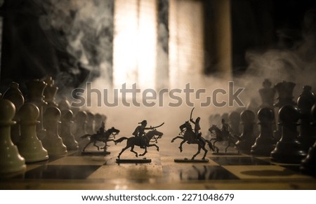 Medieval battle scene with cavalry and infantry on chessboard. Chess board game concept of business ideas and competition and strategy ideas Chess figures on a dark background with smoke and fog. Royalty-Free Stock Photo #2271048679