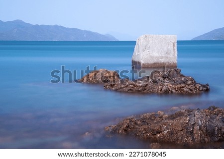 An abandoned concrete block just off shore.  Mountains in the background