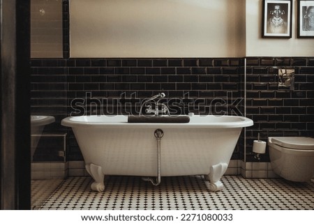 Timeless beauty with this black and white bathroom with freestanding tub and black glossy tiles. This exquisite wellness inspired interior design transforms your space into glistening elegance.  Royalty-Free Stock Photo #2271080033