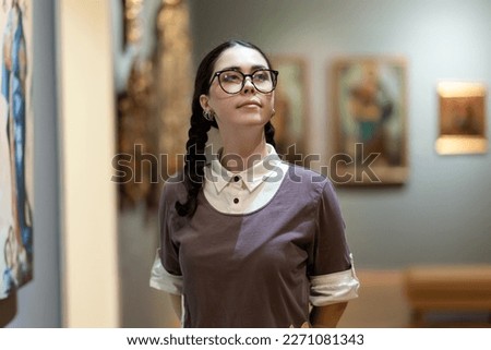 Portrait of young Caucasian pretty woman contemplates arts. Student visiting arts exhibition. Museum day. Concept of modern culture education. Royalty-Free Stock Photo #2271081343
