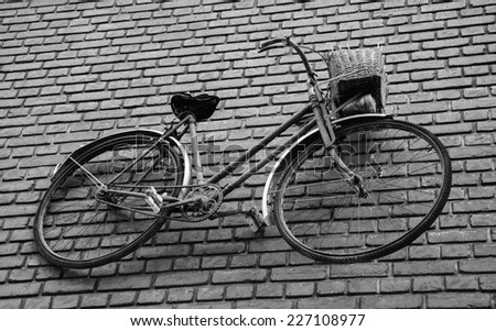 Old rusty bike attached to red brick wall. Aged photo. Black and white.