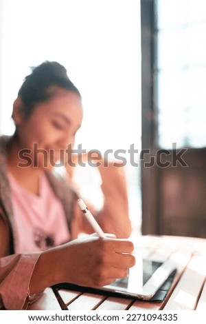 A selective focus picture of a young woman's hand drawing a design in her digital tablet