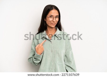 hispanic pretty woman looking proud, confident and happy, smiling and pointing to self or making number one sign