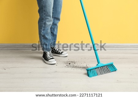 Woman sweeping floor with broom Royalty-Free Stock Photo #2271117121