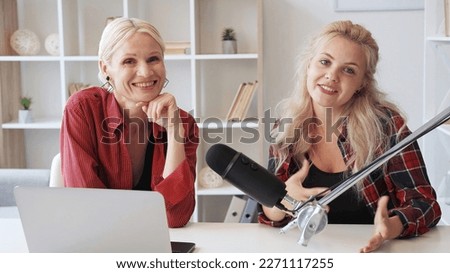 Talk show. Video blog. Interview broadcast. Live streaming. Cheerful influencer women speaking in studio interior with microphone and laptop.