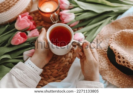 Girl holding a cup of tea in a cozy home interior.