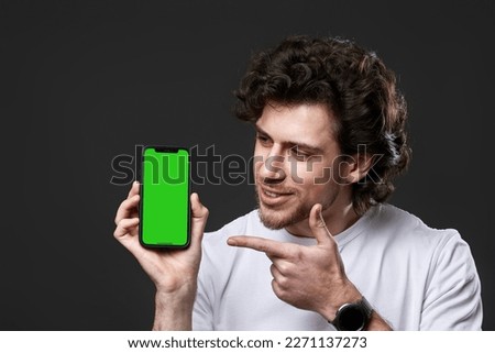 happy young man showing phone with green screen