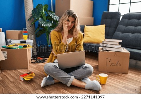 Young woman sitting on the floor at new home using laptop thinking looking tired and bored with depression problems with crossed arms. 