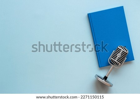 Recording audiobook or podcast with microphone and book, top view.