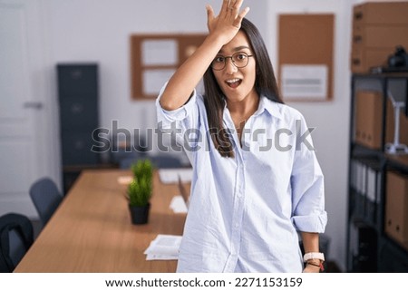 Young hispanic woman at the office surprised with hand on head for mistake, remember error. forgot, bad memory concept.  Royalty-Free Stock Photo #2271153159