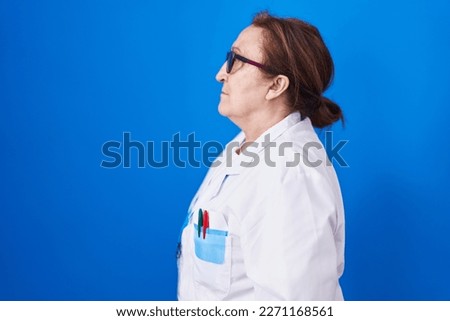 Senior woman with glasses wearing scientist uniform looking to side, relax profile pose with natural face with confident smile. 