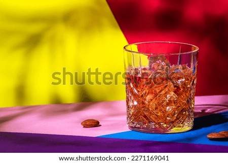 French connection cocktail with cognac and amaretto liqueur. Modern style still life on fashionable multicolored background