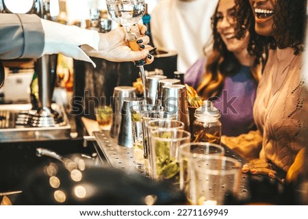 Bartender pouring alcohol from the bottle into the glasses - Happy friends group hanging out on weekend night at cocktail bar venue - Life style concept with barman making drinks and serves customers  Royalty-Free Stock Photo #2271169949