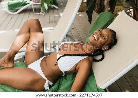 Happy African American tourist lying on lounger and laughing