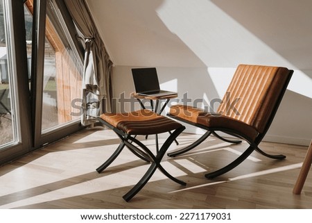 Aesthetic luxury modern home office workspace interior with laptop computer, orange leather armchair and coffee table. Sunlight shadows on the wall. Lounge space for relaxation and chill Royalty-Free Stock Photo #2271179031