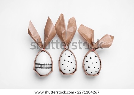 Easter bunnies made of craft paper and eggs on white background, flat lay