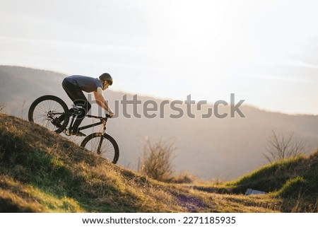 A man on a mountain bike rides downhill in beautiful nature. Royalty-Free Stock Photo #2271185935