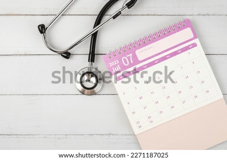 June 2023 desk calendar and stethoscope medical on wooden background, schedule to check up healthy concepts.
