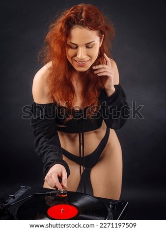 Beautiful woman about to put the needle down on the vinyl record spinning on her record player.