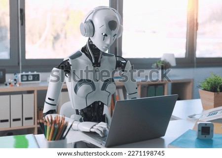 A humanoid robot works in an office on a laptop to listening Music in  Headphone, showcasing the utility of automation in repetitive and tedious tasks. Royalty-Free Stock Photo #2271198745