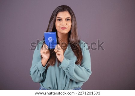 Horizontal photo. Beautiful Brazilian woman, with casual clothes, Jeans and green shirt. holding work card and social security. Document.