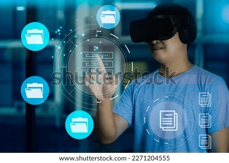Metaverse and virtual reality technoloty. Asian man in blue t shirt touching virtual screen connecting with big world data blurred building background.