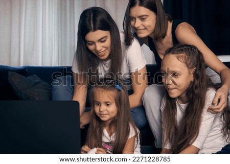  Staged photo. A lesbian couple and their children are having a good time at home.    The whole family gathered around the screen watching cartoons. The girls are having a lot of fun.                 