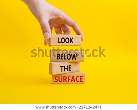 Look below the surface symbol. Concept word Look below the surface on wooden blocks. Beautiful yellow background. Businessman hand. Business and Look below the surface concept. Copy space