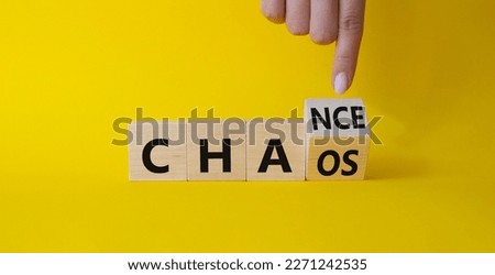 Chance vs Chaos symbol. Businessman hand points at Turned wooden cubes with words Chaos and Chance. Beautiful yellow background. Psychology and Chance vs Chaos concept. Copy space
