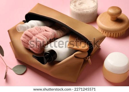 Preparation for spa. Compact toiletry bag with different cosmetic products on pink background, closeup Royalty-Free Stock Photo #2271245571