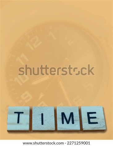 selective focus on the arrangement of the black alphabet in a blue box with a brown background and there is a blurred image of a clock
