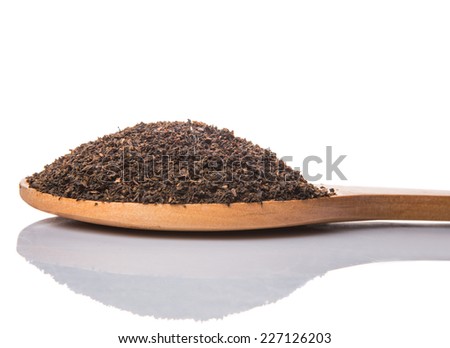 Dried, processed and blended tea leaves in wooden spoon over white background
