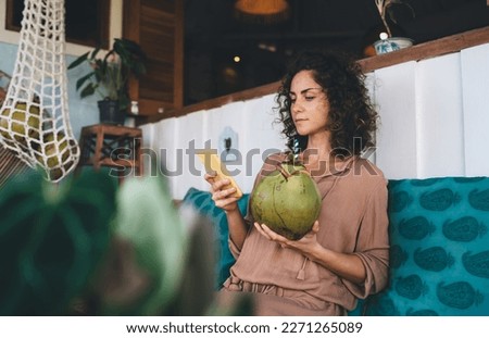 Caucaisan woman with tropical beverage using cellphone device for chatting and messaging in social media, millennial female with modern smartphone connecting to 4g wireless for browsing website