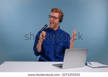 male podcast host actively shouting into microphone on blue background