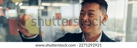 Close up of asian businessman is glues sticky notes on motivation board in modern office