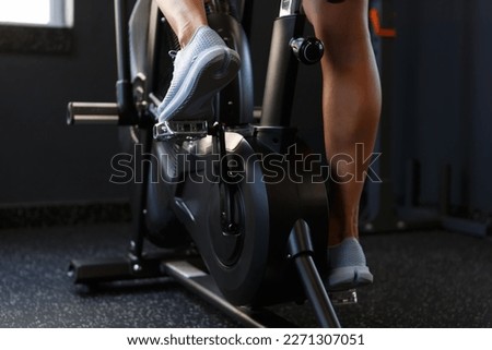 Feet of young female athlete exercising on elliptical trainer machine in the gym. Athletic woman cycling indoors on modern orbitrek equipment Royalty-Free Stock Photo #2271307051