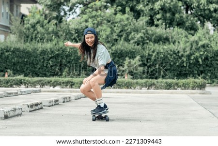 Portrait beautiful sportive Asian female skater wearing hipster shirt with shorts, smiling with happiness, standing on skateboard and playing outdoor with copy space. Activity and Adventure Concept Royalty-Free Stock Photo #2271309443