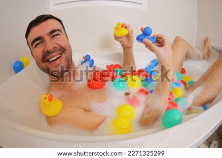 Adult man playing with rubber ducks in the bathtub 