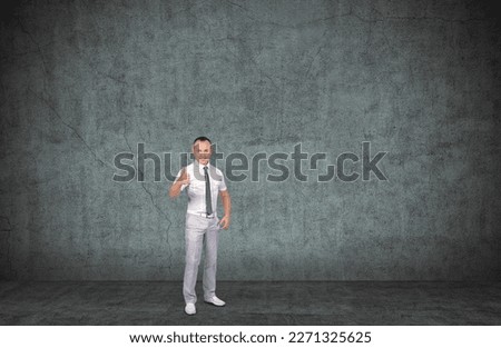 Young smiling businessman showing thumbs up sign. Modern concrete interior.  Successful happy entrepreneur and business concept