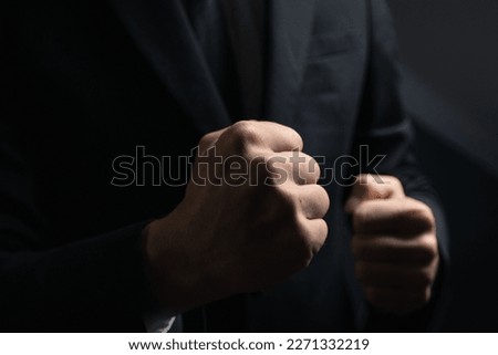 A man in a black suit with his fists up