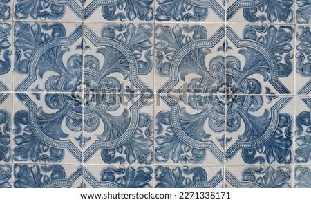 Vintage ceramic tiles of faded blue colour with floral repetitive ornate in Lisbon, Portugal. Authentic Portuguese tiling art.