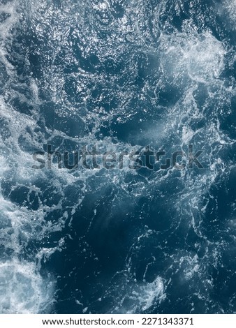 Abstract background. The waves of the sea water meet with underwater pointed rocks, forming whirlpools.Sea water with foam abstract background. Turquoise water with waves