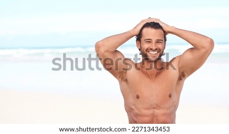 This is the life for me. An attractive young man on the beach slicking back his hair. Royalty-Free Stock Photo #2271343453