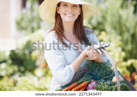 Good food is wise medicine. A gorgeous woman in a straw hat holding a basket of fresh vegetables in her garden. Royalty-Free Stock Photo #2271343497