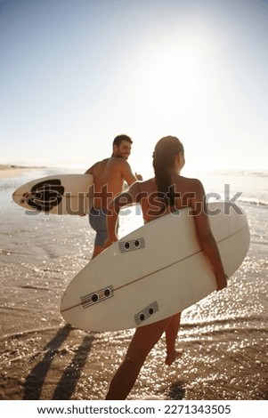 Ill race you. Rearview shot of a young surfer couple running into the sea together. Royalty-Free Stock Photo #2271343505