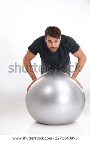 Balancing fitness and strength. Studio shot of a young man doing pushups on an exercise ball.