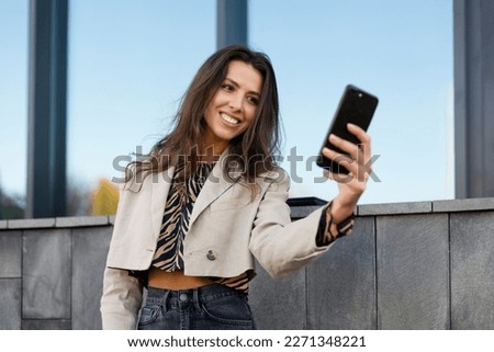 Attractive, young girl taking a selfie on a mobile phone. A beautiful influencer communicates with her followers, records videos.